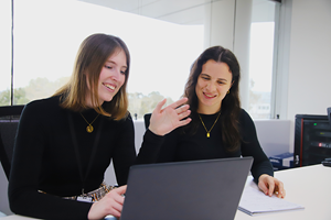 Two graduates looking at a laptop screen