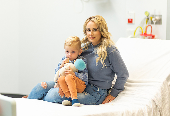 Mother holds her toddler on a hospital bed